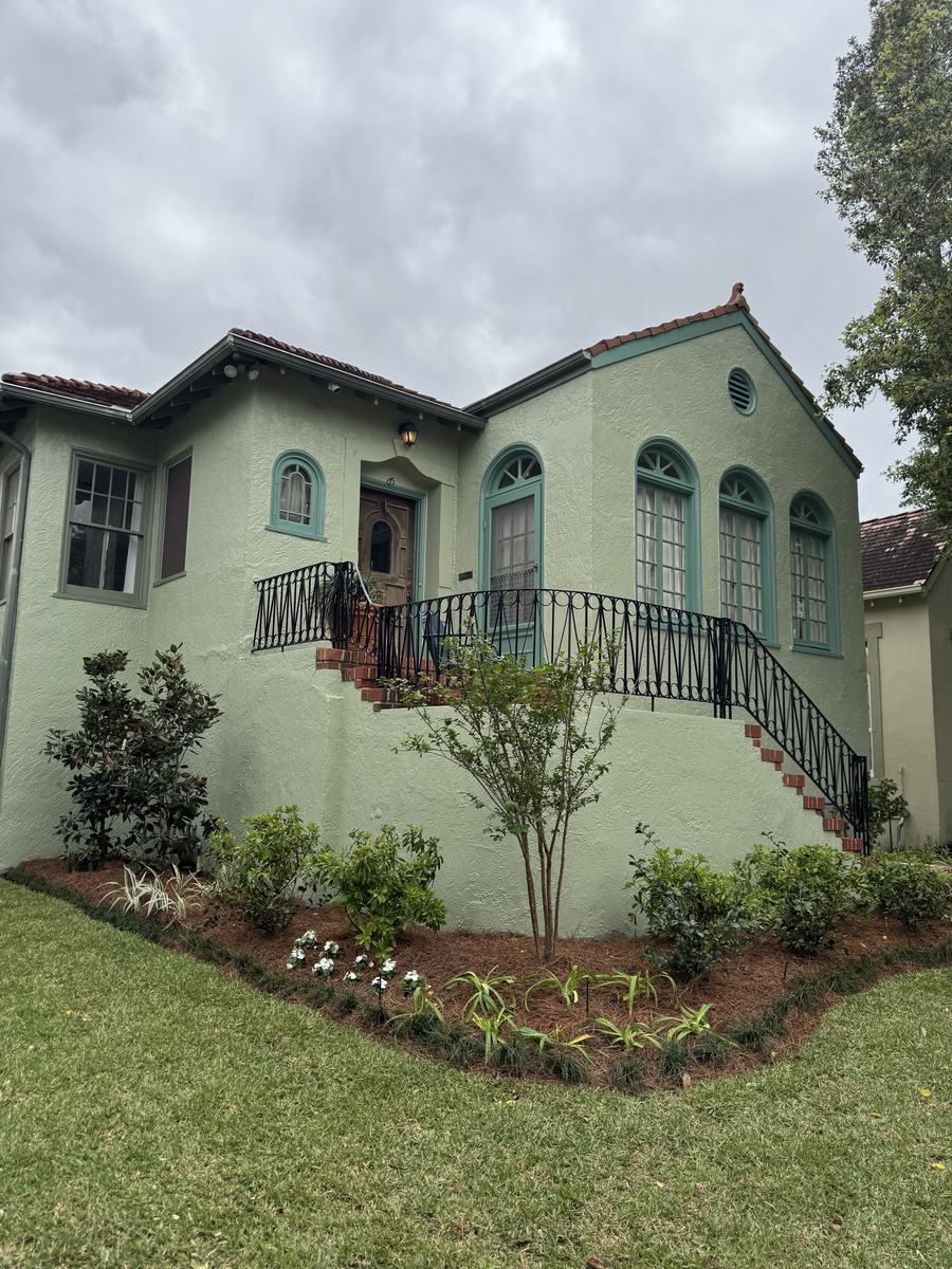 After: the same house with a curved bed, a crape myrtle, shrubs and new sod