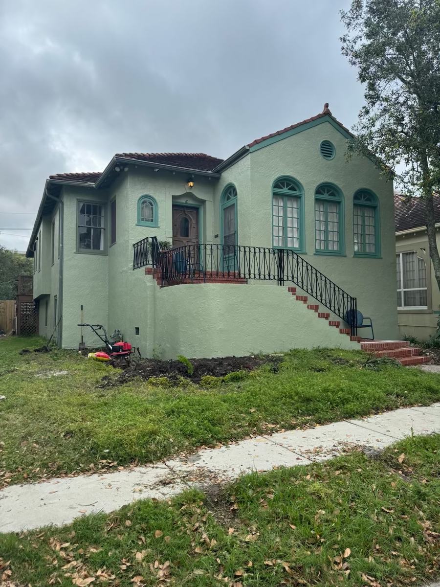 Before: a stucco house with a torn-up front yard and a mower on the lawn