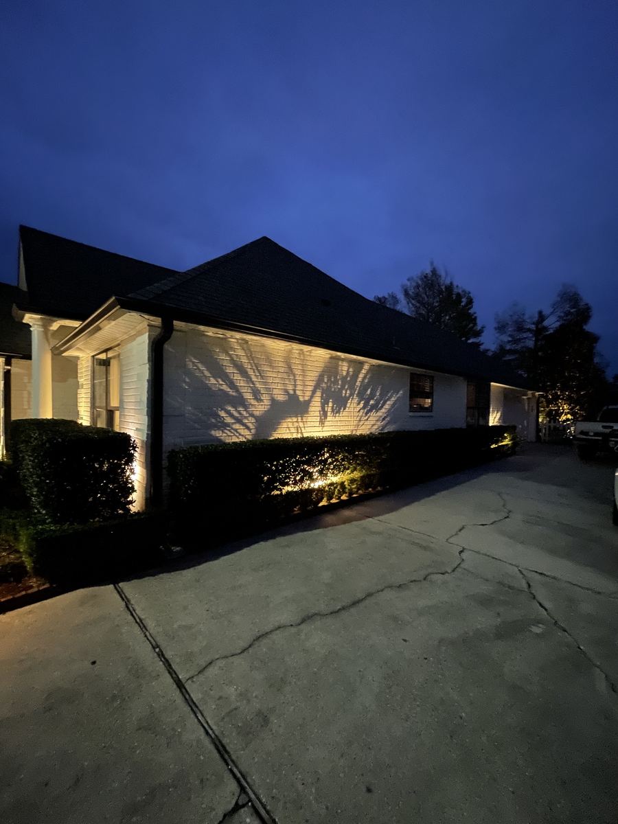 Uplighting along a white-brick house at night