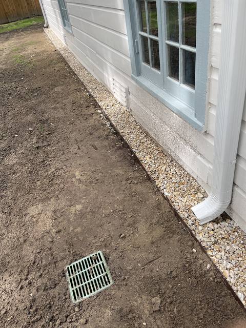A side yard with a gravel drip strip, a catch-basin drain and a downspout tie-in