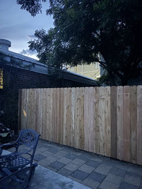 A new cedar privacy fence over a paver patio at dusk