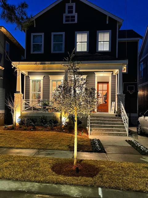 A whole facade at dusk: a new specimen tree with an uplight, lit porch and new sod